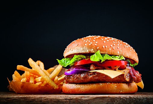 Photo d'un burger accompagné de frites sur fond noir 