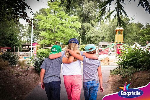 Groupe de 3 enfants se tenant par les épaules et marchant en direction d'Air Baggy, l'une des attractions du parc Bagatelle