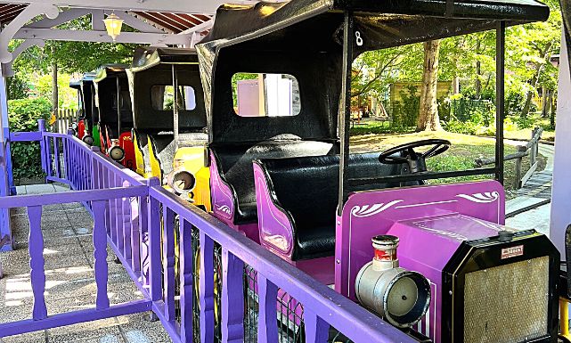Zoom sur les véhicules de l'attraction des Tacots en gare, présents dans toutes les couleurs