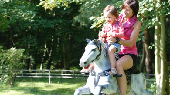 Photo d'une maman et sa fille assise sur un des chevaux de l'attraction O'Galop du parc Bagatelle